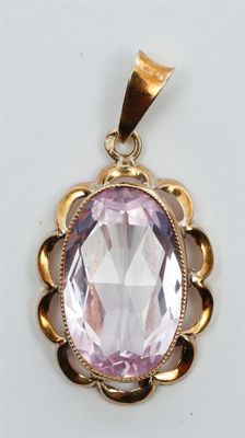 un pendentif en or orné d'une grosse pierre rose au centre