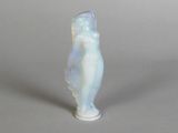 a small glass figurine of a woman on a gray surface