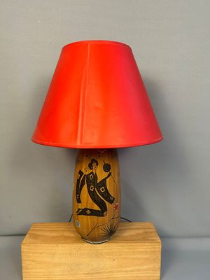 une lampe de table en bois surmontée d'un abat-jour rouge
