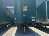 three green semi trucks parked in a parking lot