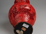 a red vase with a black lid sitting on a table