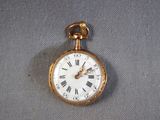 a gold pocket watch with roman numerals on it