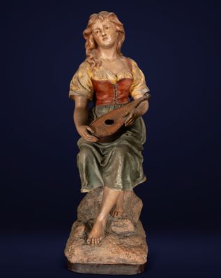 une statue représentant une femme assise sur un rocher, tenant une guitare