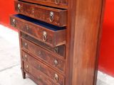 a small wooden chest of drawers against a red wall
