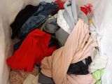 a white container filled with lots of clothes on the floor