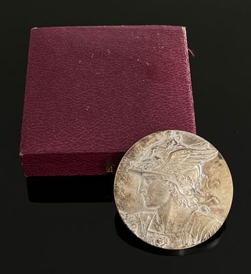 une vieille pièce d'argent posée à côté d'une boîte rouge sur une surface noire