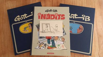 three books are sitting on a wooden table, one of which has a drawing of a man and the other of which has a picture of a cat