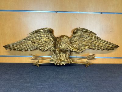 un gros plan d'un aigle royal tenant une flèche, posé sur une table