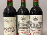 three bottles of red wine are lined up on a table
