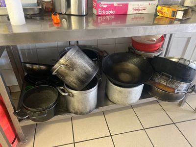 de nombreuses casseroles et poêles posées sur une étagère dans la cuisine