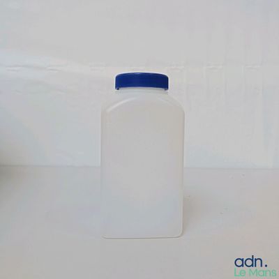 une bouteille en plastique avec un bouchon bleu posée sur une surface blanche
