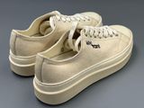 beige sued sneakers with white laces on a grey surface