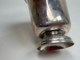 a silver cup on a white table with a red handle