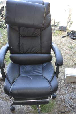 une chaise de bureau noire posée dans l'herbe