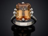 an orange topazte and diamond ring on a black surface