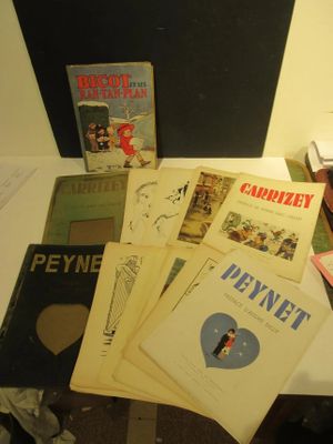 Plusieurs livres sont empilés sur une table, à côté d'une lampe.