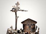 a silver figurine of a dog, a house, and a tree