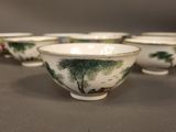 four chinese bowls with trees painted on them sit on a table