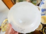a person holding a white plate on top of a table
