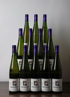 Des bouteilles de vin sont alignées sur une table devant un mur blanc