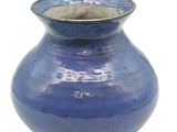 un vase bleu posé sur une surface blanche
