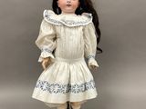 une poupée en porcelaine représentant une petite fille vêtue d'une robe blanche et de chaussures noires