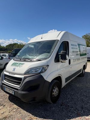 une camionnette blanche garée sur un parking, avec d'autres véhicules en arrière-plan