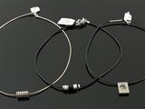 paire de boucles d'oreilles créoles en argent avec un cordon en cuir noir et des breloques en argent