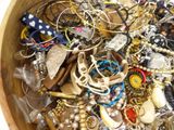 a wooden bowl filled with assorted jewelry and bracelets