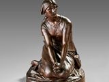 a bronze statue of a woman sitting on top of a pillow