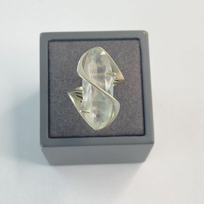 bague en argent sertie d'un quartz transparent, présentée dans un écrin posé sur un fond blanc