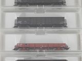 trois wagons sont placés dans une boîte transparente posée sur une surface blanche