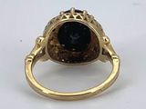 a close up of a gold ring with a black stone