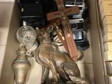 une boîte remplie d'objets divers, parmi lesquels un appareil photo, une horloge et une statuette