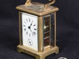 a small gold clock with a key on a black background