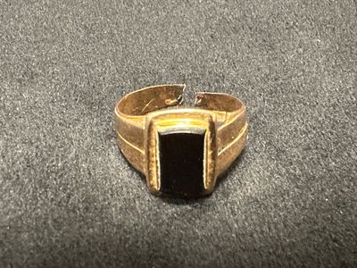 Gros plan sur une bague en or ornée d'une pierre noire