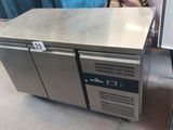 a stainless steel counter with two doors and a woman in the background