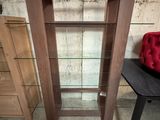 une étagère en bois avec des tablettes en verre, placée dans un coin de la pièce