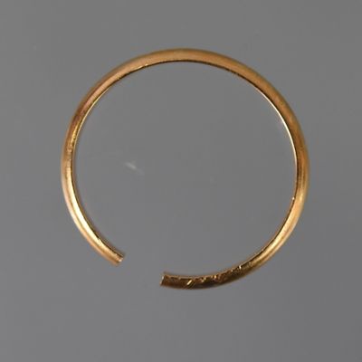 gros plan d'une bague en or sur une surface grise