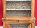 an old wooden china cabinet with open doors and a red wall behind it