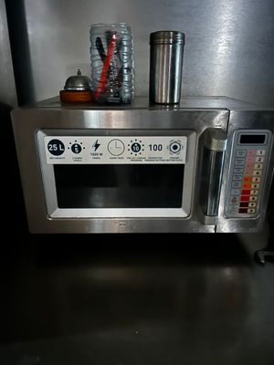 a silver microwave with a cup on top of it