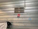 une photo d'une porte de garage métallique avec un matelas posé à même le sol