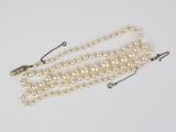 a close up of a pearl necklace with a clasp on a white surface