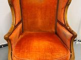 une chaise orange dans une pièce, avec un mur blanc en arrière-plan