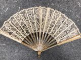 a close up of a white lace fan on a gray surface