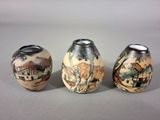 three vases with different designs on them sitting on a table