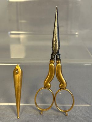 a pair of scissors sitting next to a gold object