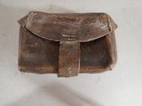 a small brown leather bag on a white surface