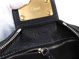 a person holding a black purse with a gold tag on it