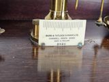 a gold clock on a table with a ruler on it